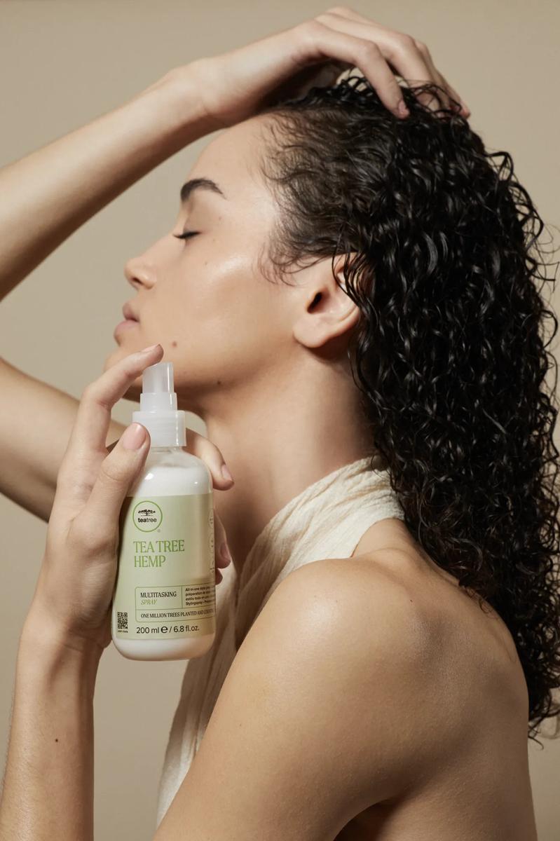image of a woman holding a bottle of Tea Tree Hemp Multitasking Spray