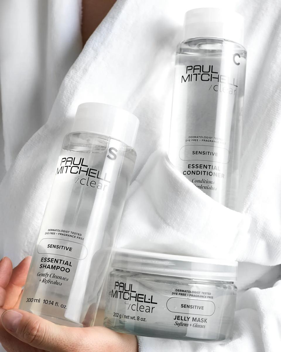 close up image of a person holding Essential Shampoo, Essential Conditioner and Clear Jelly Mask