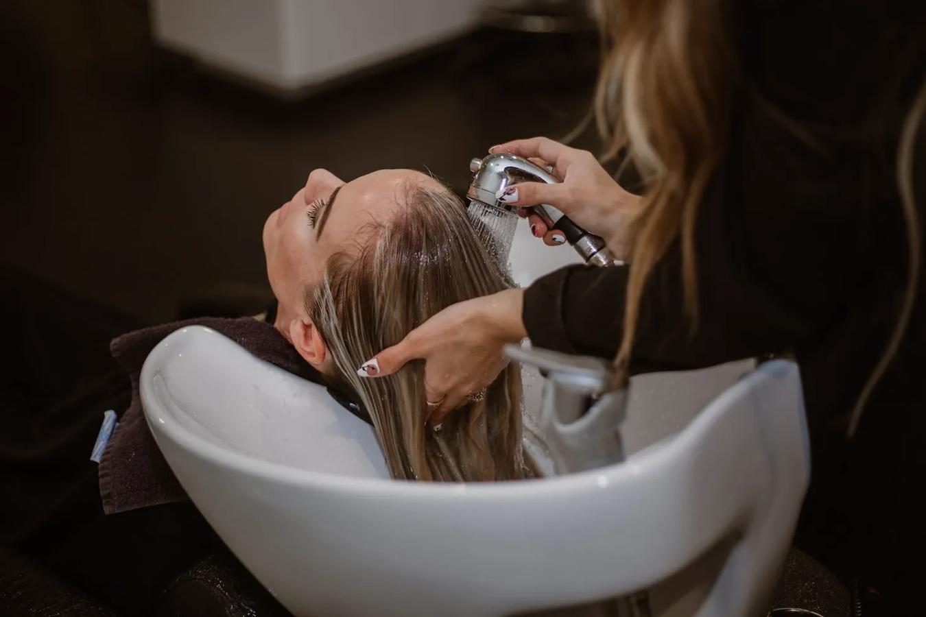 A woman getting her hair washed in a basin by a hairstylist