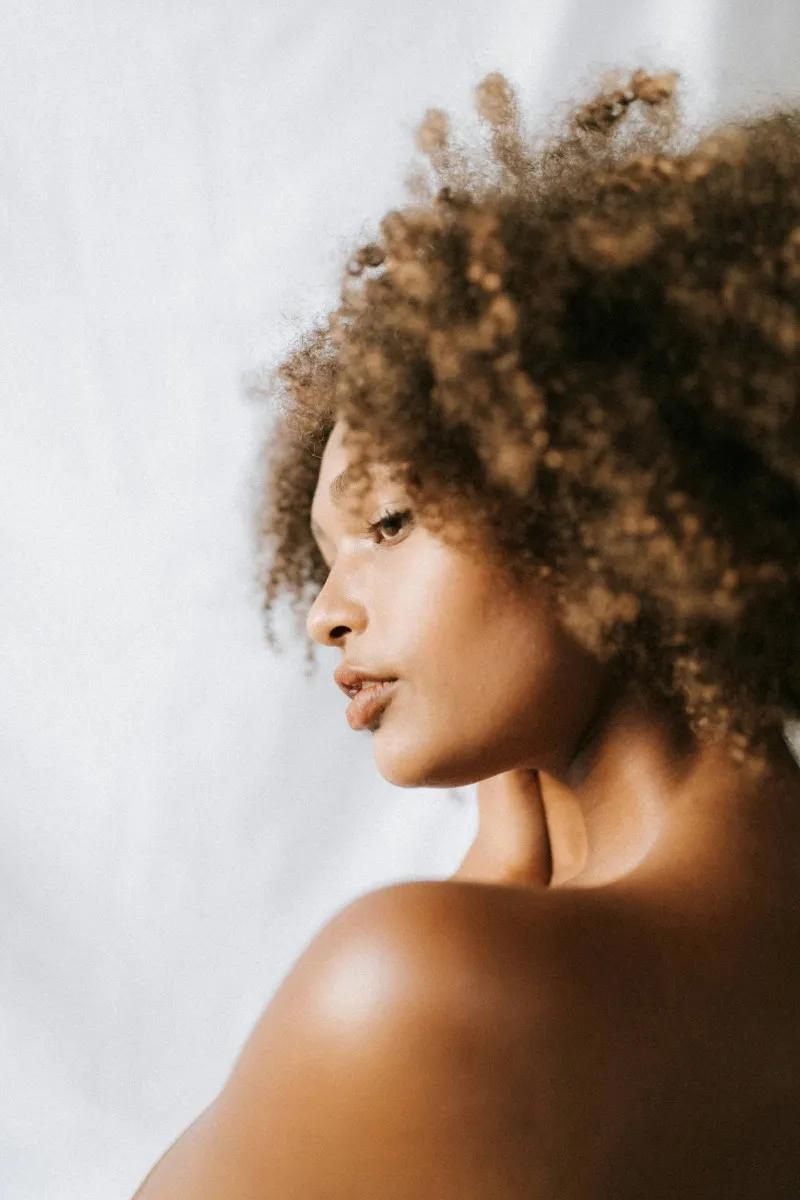 a woman with brown curly hair looking over her shoulder