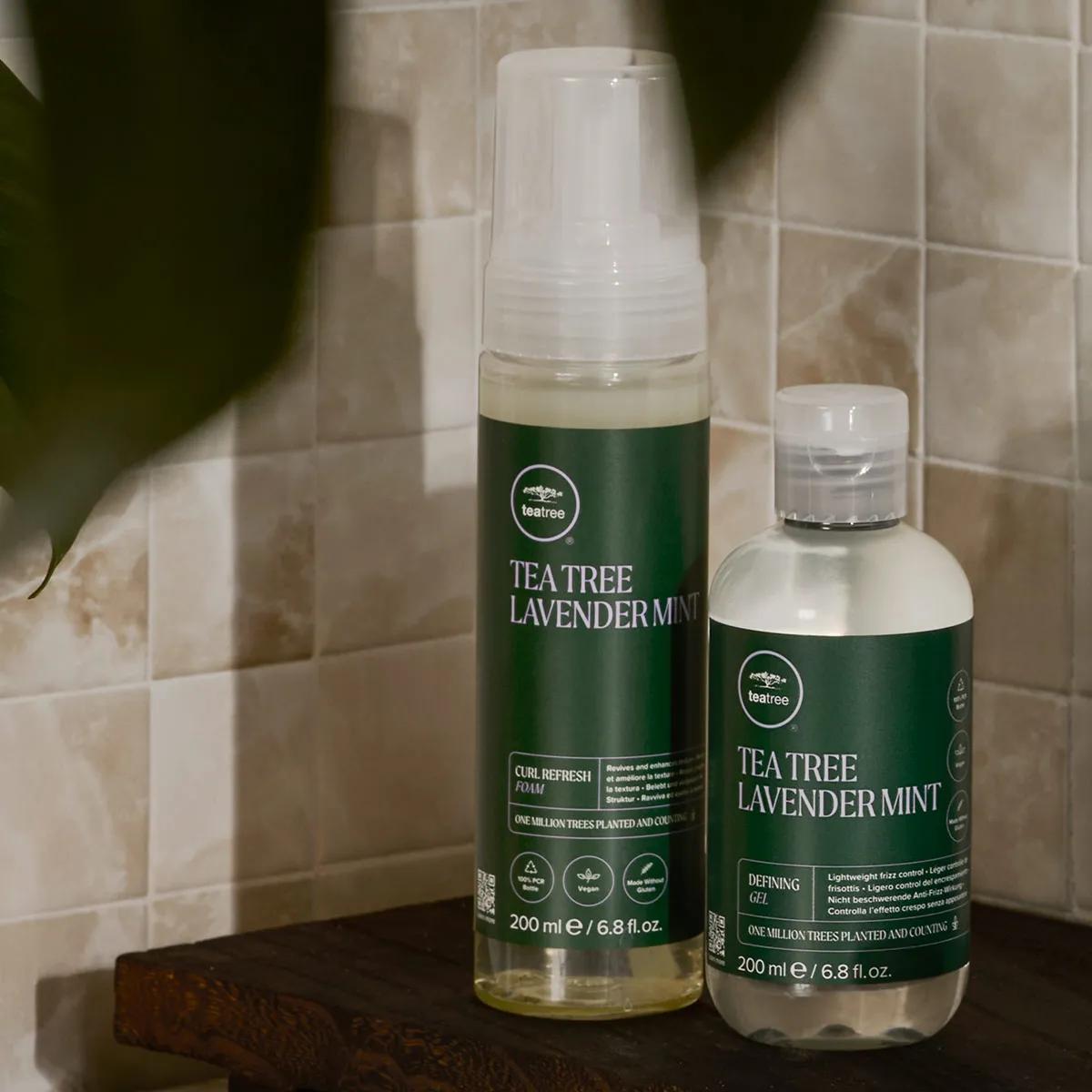 image of a model holding a bottle of Lavender Mint Curl Refresh Foam and a bottle of Lavender Mint Defining Gel