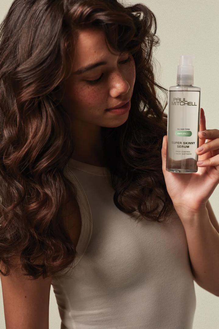 image of a brunette model holding a bottle of Super Skinny Serum