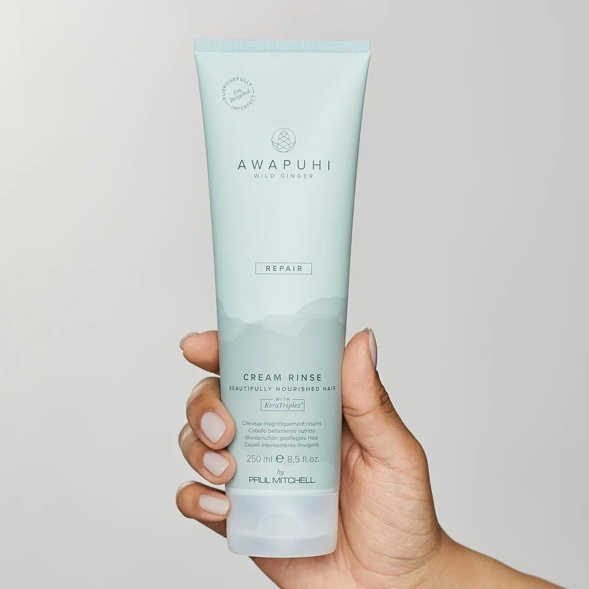 image of a model holding a tube of Awapuhi KeraTriplex Cream Rinse