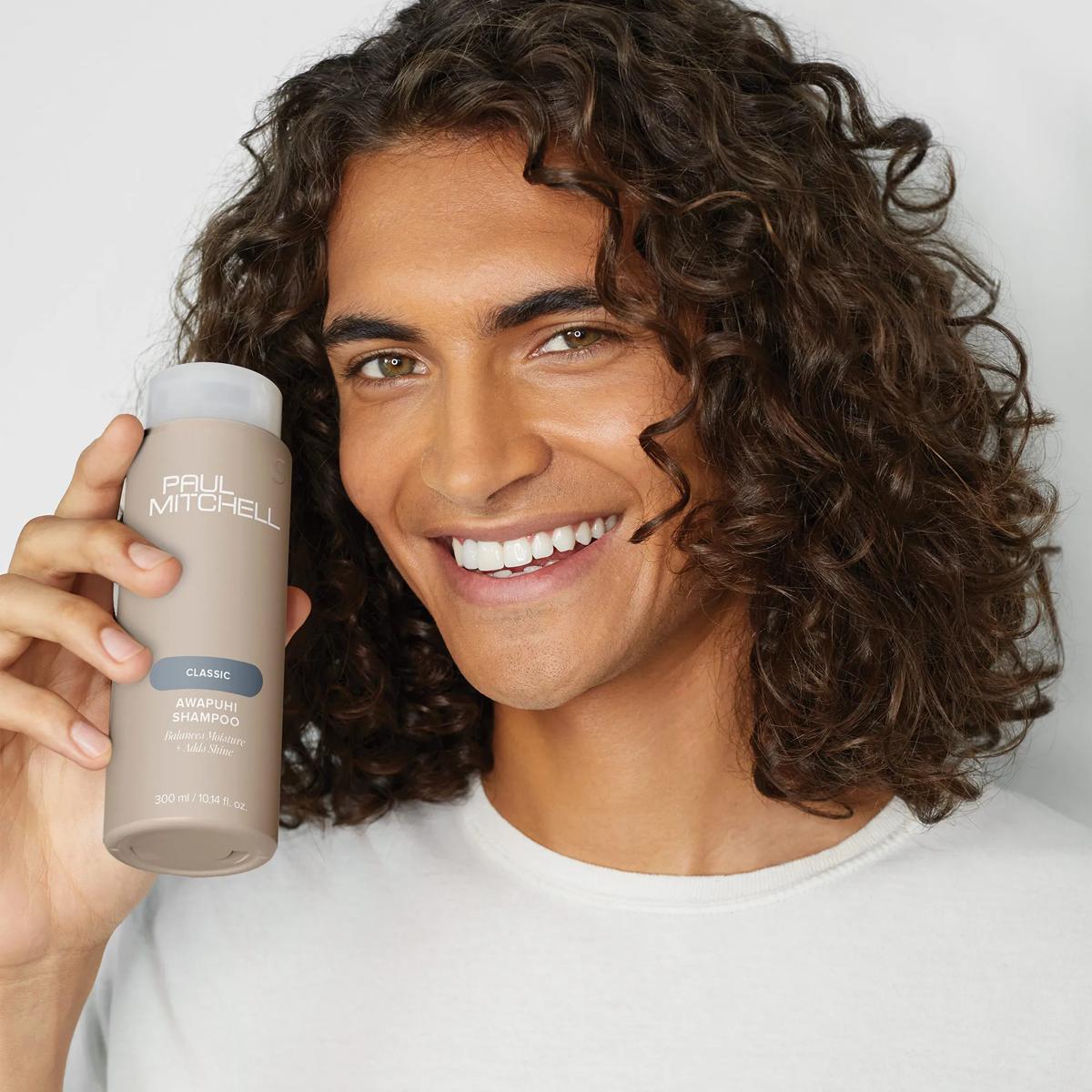 image of a model holding a bottle of Awapuhi Shampoo