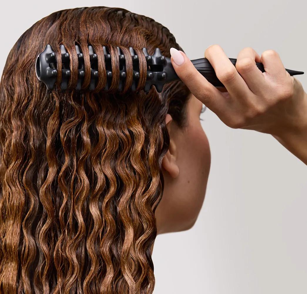close up image of a person brushing their hair with the Paul Mitchell Curl Brush